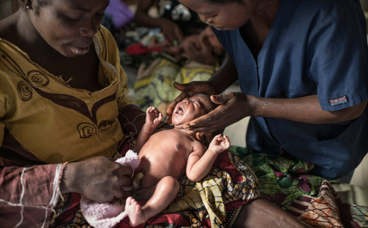 Photo of a health worker providing umbilical cord care to a newborn while the mother watches.